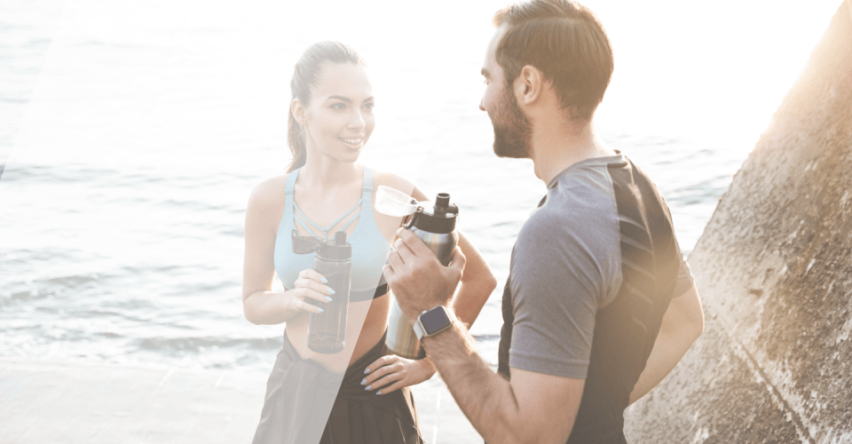 une femme et un homme qui font une pause pendant leur séance de sport, avec une gourde à la maion