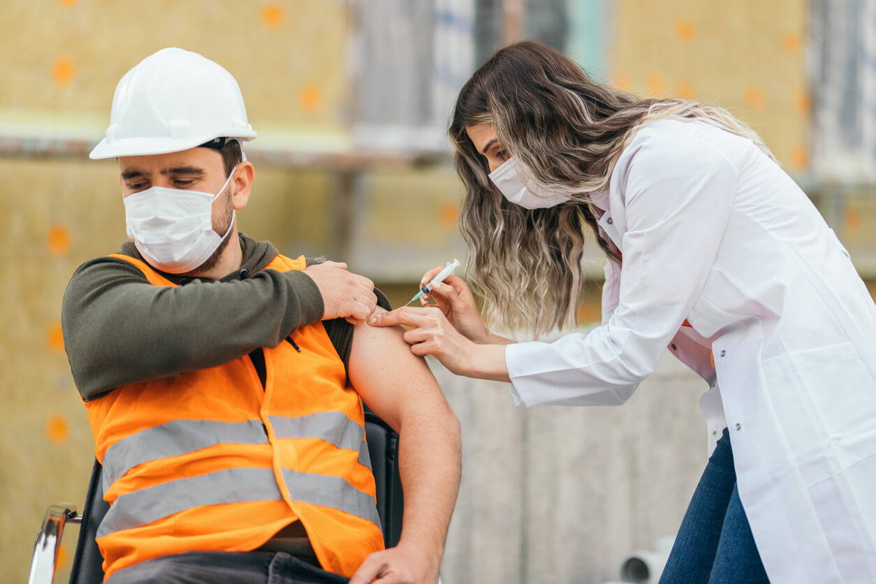 infirmière du travail qui soigne un ouvrier avec une piqûre