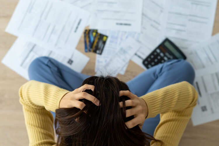 Une personne se tient la tête de désarroi face à des courriers et des factures provenant de son assureur maladie. 